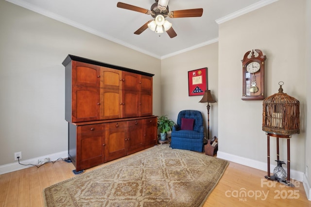 living area featuring light wood finished floors, ceiling fan, baseboards, and crown molding