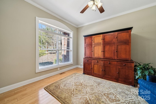 sitting room with light wood finished floors, baseboards, visible vents, ceiling fan, and ornamental molding