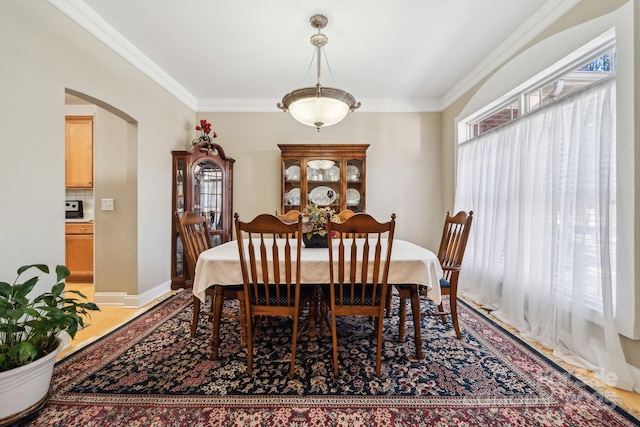 dining room featuring a healthy amount of sunlight, arched walkways, and crown molding