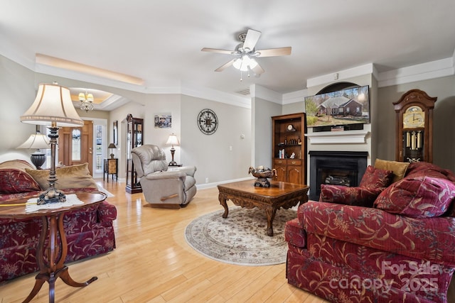 living area featuring arched walkways, a fireplace, visible vents, ornamental molding, and light wood-type flooring
