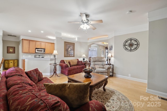 living room featuring baseboards, arched walkways, ceiling fan, light wood-style floors, and recessed lighting