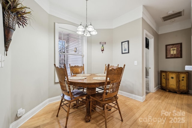 dining space featuring light wood-style floors, baseboards, visible vents, and a chandelier