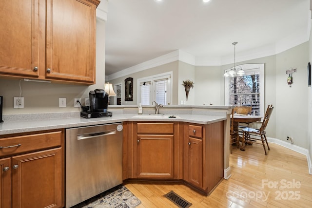 kitchen featuring visible vents, dishwasher, a peninsula, hanging light fixtures, and light countertops
