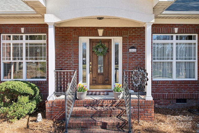 doorway to property with crawl space, a shingled roof, and brick siding