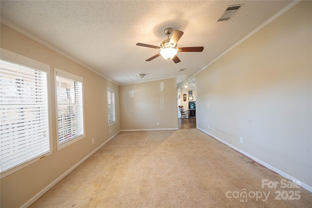 empty room featuring ornamental molding, light colored carpet, visible vents, and a textured ceiling