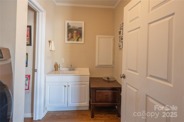 bathroom featuring wood finished floors, ornamental molding, vanity, and washer / dryer