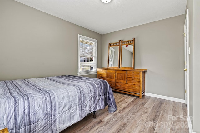 bedroom with light wood-style flooring and baseboards