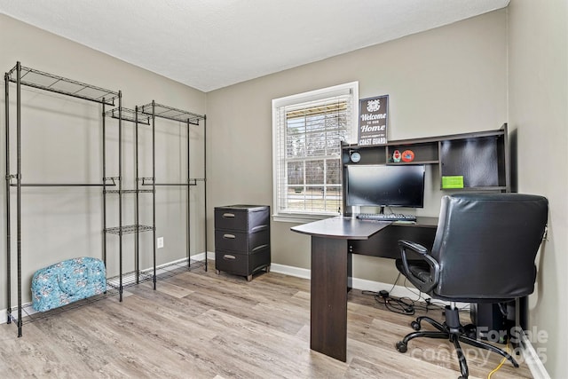 office area with light wood-style floors, a textured ceiling, and baseboards