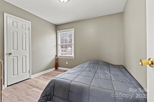 bedroom with a textured ceiling, baseboards, and wood finished floors