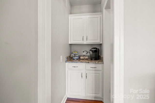 bar featuring a textured ceiling and baseboards