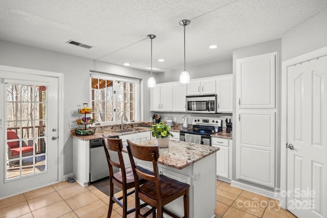 kitchen featuring appliances with stainless steel finishes, white cabinets, visible vents, and a kitchen breakfast bar