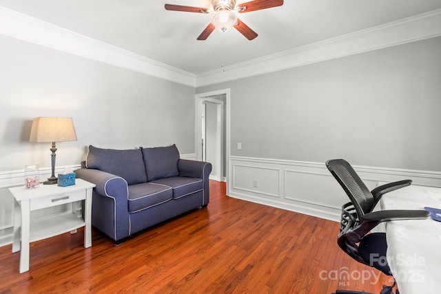 office area with ornamental molding, a ceiling fan, wainscoting, and wood finished floors