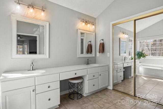 bathroom with lofted ceiling, double vanity, a sink, and a garden tub