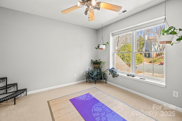 exercise area featuring baseboards, visible vents, a ceiling fan, a textured ceiling, and carpet flooring