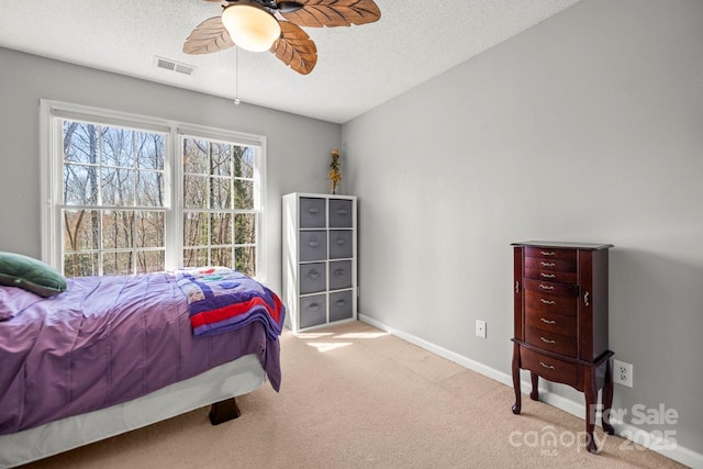 bedroom featuring light carpet, baseboards, visible vents, and a textured ceiling