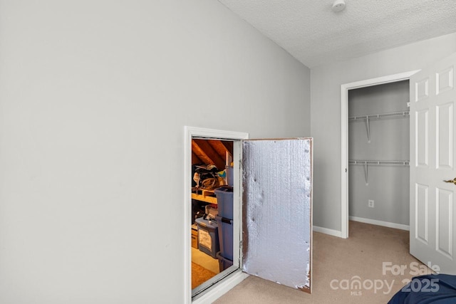 bedroom featuring light carpet, a textured ceiling, baseboards, and a closet