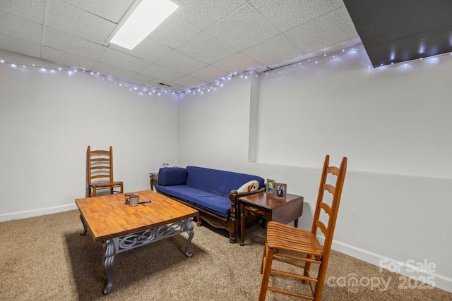 living area with a paneled ceiling, baseboards, and carpet flooring