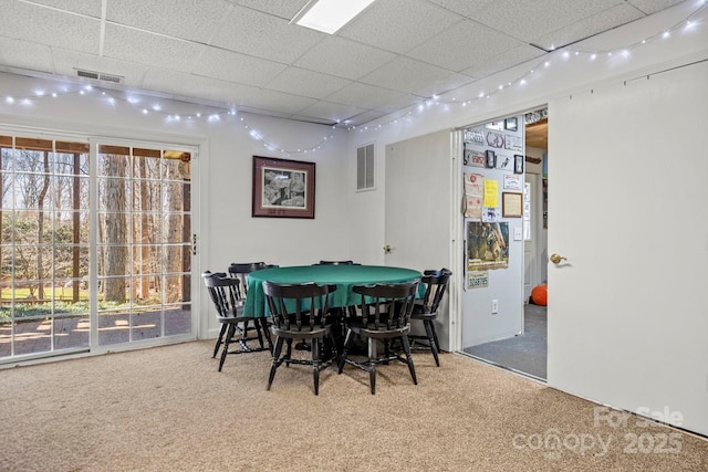 carpeted dining room with visible vents and a drop ceiling