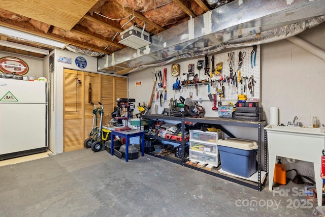 interior space with freestanding refrigerator, concrete block wall, and a workshop area