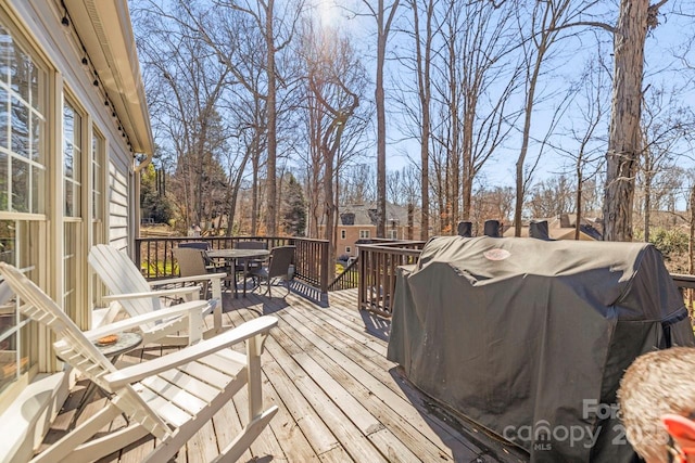 wooden deck with outdoor dining area and area for grilling