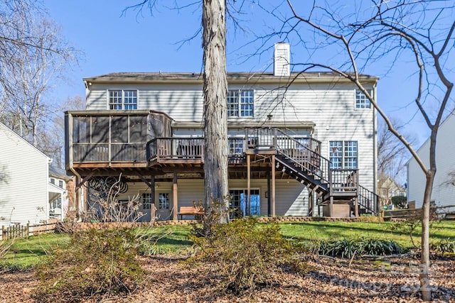 rear view of house with a sunroom, a chimney, stairs, a deck, and a yard