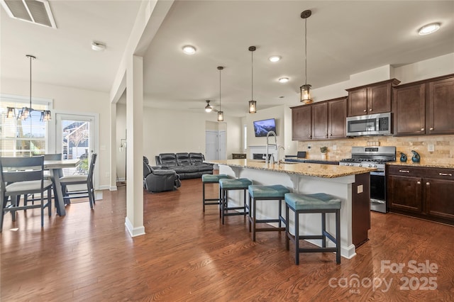 kitchen featuring appliances with stainless steel finishes, visible vents, backsplash, and light stone counters