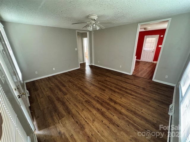 unfurnished room with a textured ceiling, dark wood-type flooring, baseboards, and ceiling fan