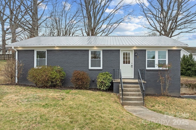 single story home featuring metal roof, brick siding, and a front lawn