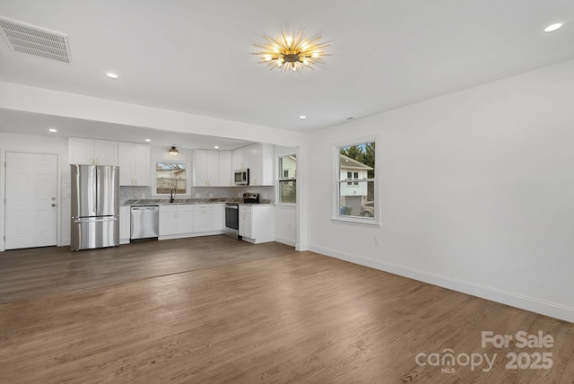 unfurnished living room featuring dark wood-type flooring, baseboards, visible vents, and a sink