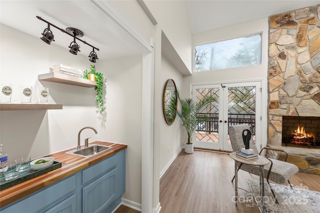 interior space featuring light wood-type flooring, french doors, a sink, and a stone fireplace