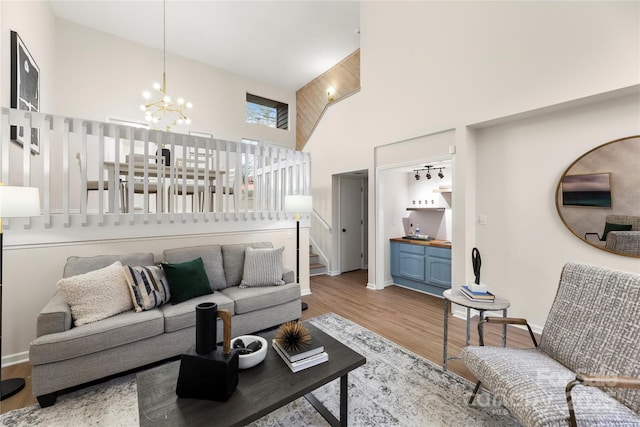 living area with a notable chandelier, a high ceiling, wood finished floors, baseboards, and stairs