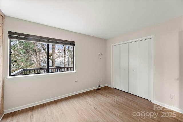 unfurnished bedroom featuring a closet, wood finished floors, and baseboards