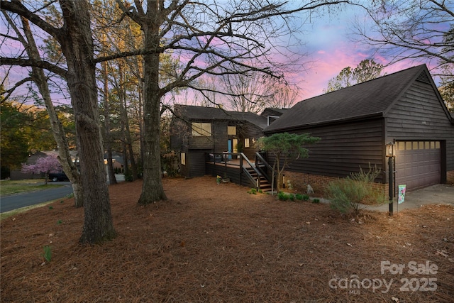 view of front of home with a garage and roof with shingles