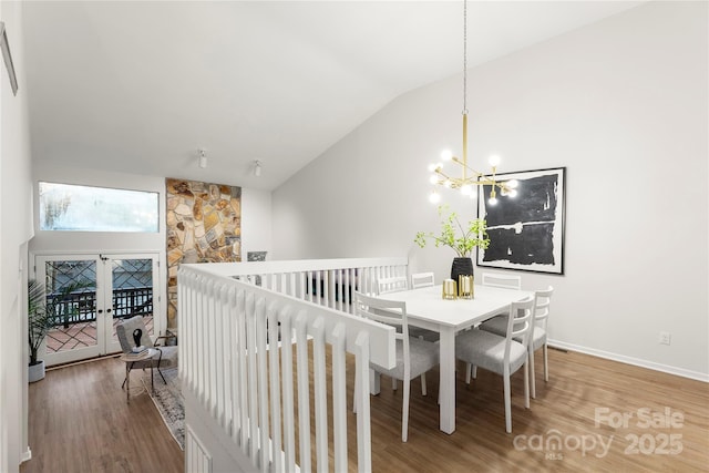 dining area featuring baseboards, a chandelier, vaulted ceiling, and wood finished floors