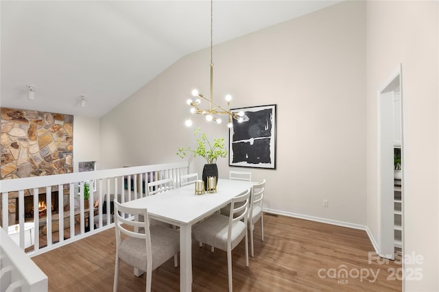 dining area with lofted ceiling, baseboards, wood finished floors, and a chandelier