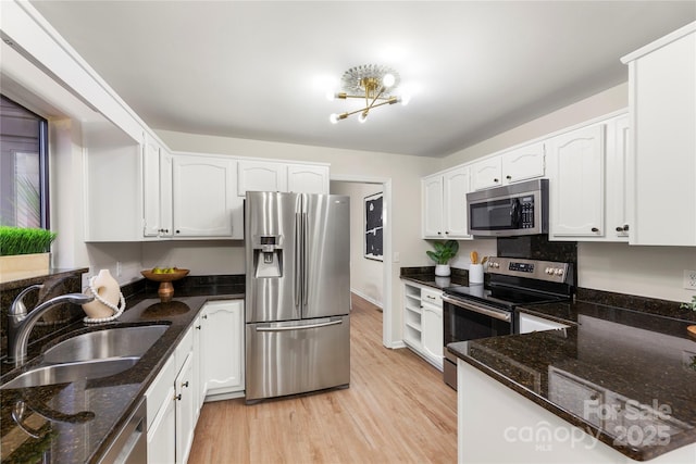 kitchen with stainless steel appliances, light wood-type flooring, a sink, and white cabinetry