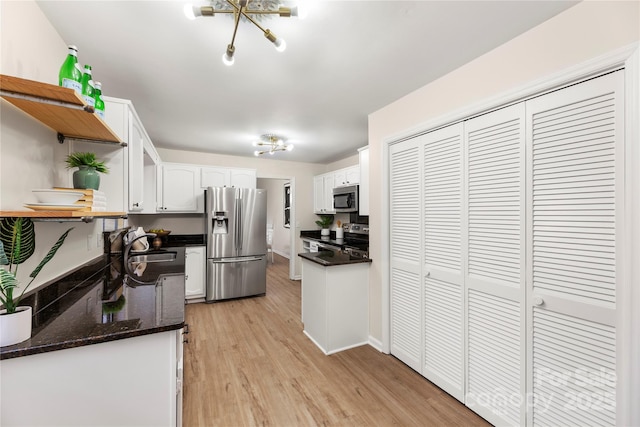 kitchen featuring white cabinets, light wood-style flooring, stainless steel appliances, open shelves, and a sink