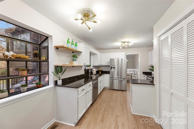 kitchen with white cabinets, appliances with stainless steel finishes, light wood-style floors, open shelves, and a sink