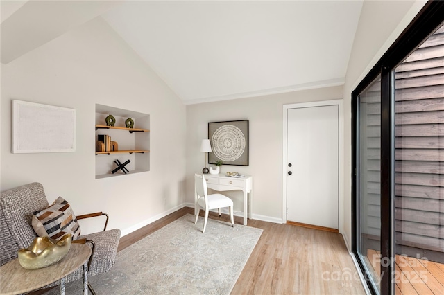 office space featuring built in shelves, baseboards, vaulted ceiling, and wood finished floors