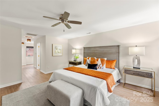 bedroom with a ceiling fan, baseboards, visible vents, and wood finished floors