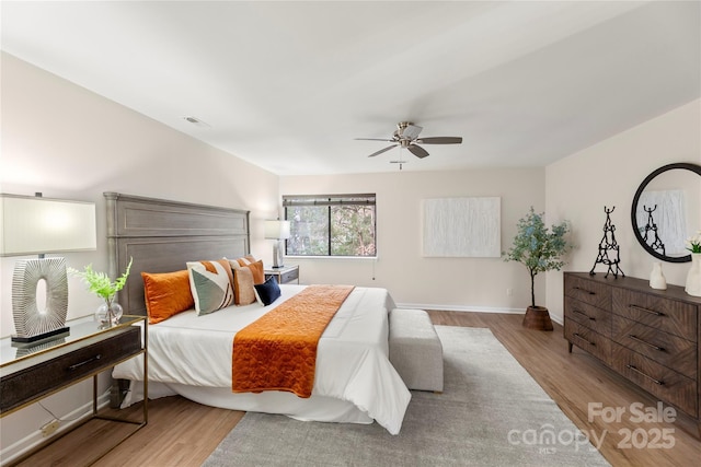 bedroom with baseboards, visible vents, a ceiling fan, and wood finished floors