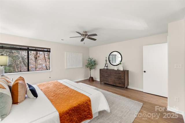 bedroom featuring a ceiling fan, baseboards, and wood finished floors