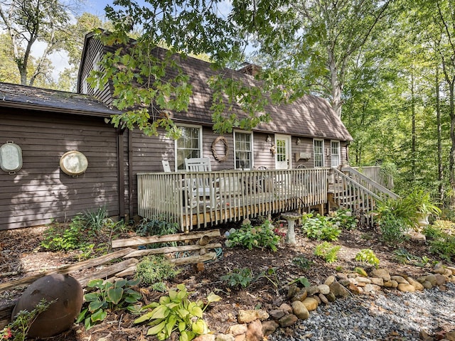 view of front facade with a deck and a shingled roof