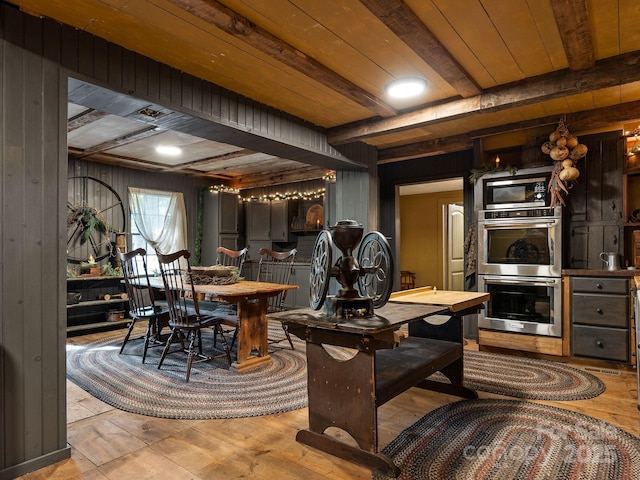 dining space featuring light wood-style flooring, wooden ceiling, a fireplace, and beam ceiling