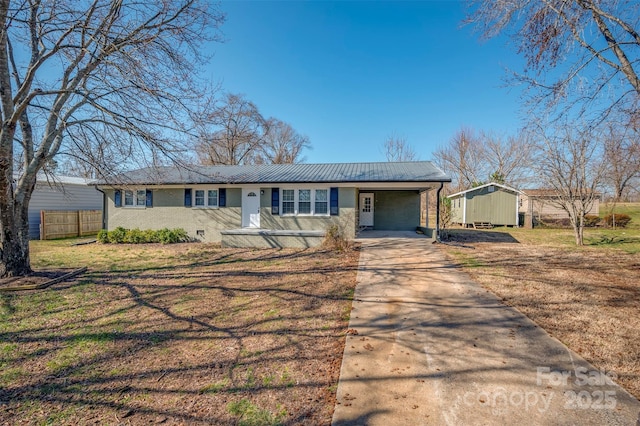 ranch-style home featuring brick siding, metal roof, fence, driveway, and a front lawn