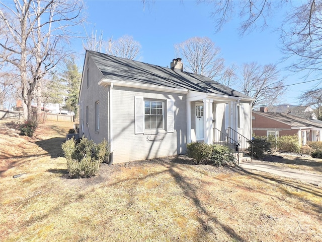 view of front of property with brick siding, fence, and a chimney