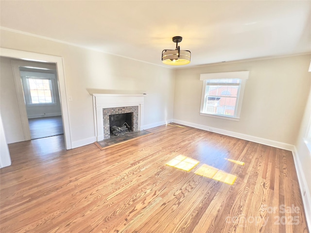 unfurnished living room featuring a fireplace with flush hearth, light wood-style flooring, and baseboards