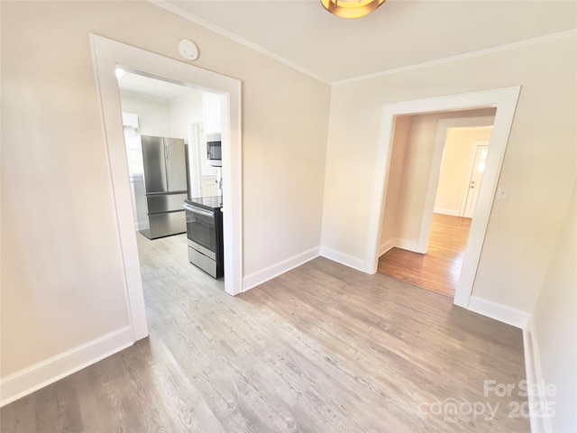 spare room with baseboards, light wood finished floors, and crown molding