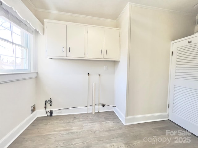 clothes washing area with washer hookup, wood finished floors, baseboards, ornamental molding, and cabinet space