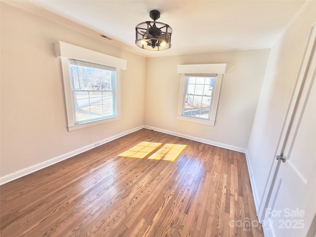 spare room featuring visible vents, wood finished floors, a wealth of natural light, and baseboards